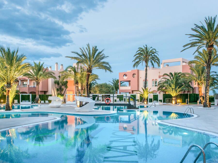 Ein Pool mit Palmen und modernen Gebäuden im Hintergrund.