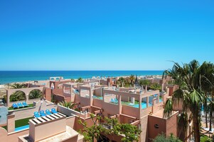 Un resort con varias construcciones, piscinas exteriores y vistas al océano.