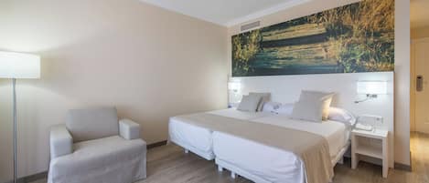 Un cuarto de hotel con una cama, mesitas de noche, una silla y un cuadro grande en la pared.