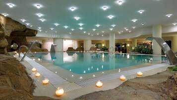 Una amplia piscina interior con un paisaje rocoso y múltiples luces en el techo.