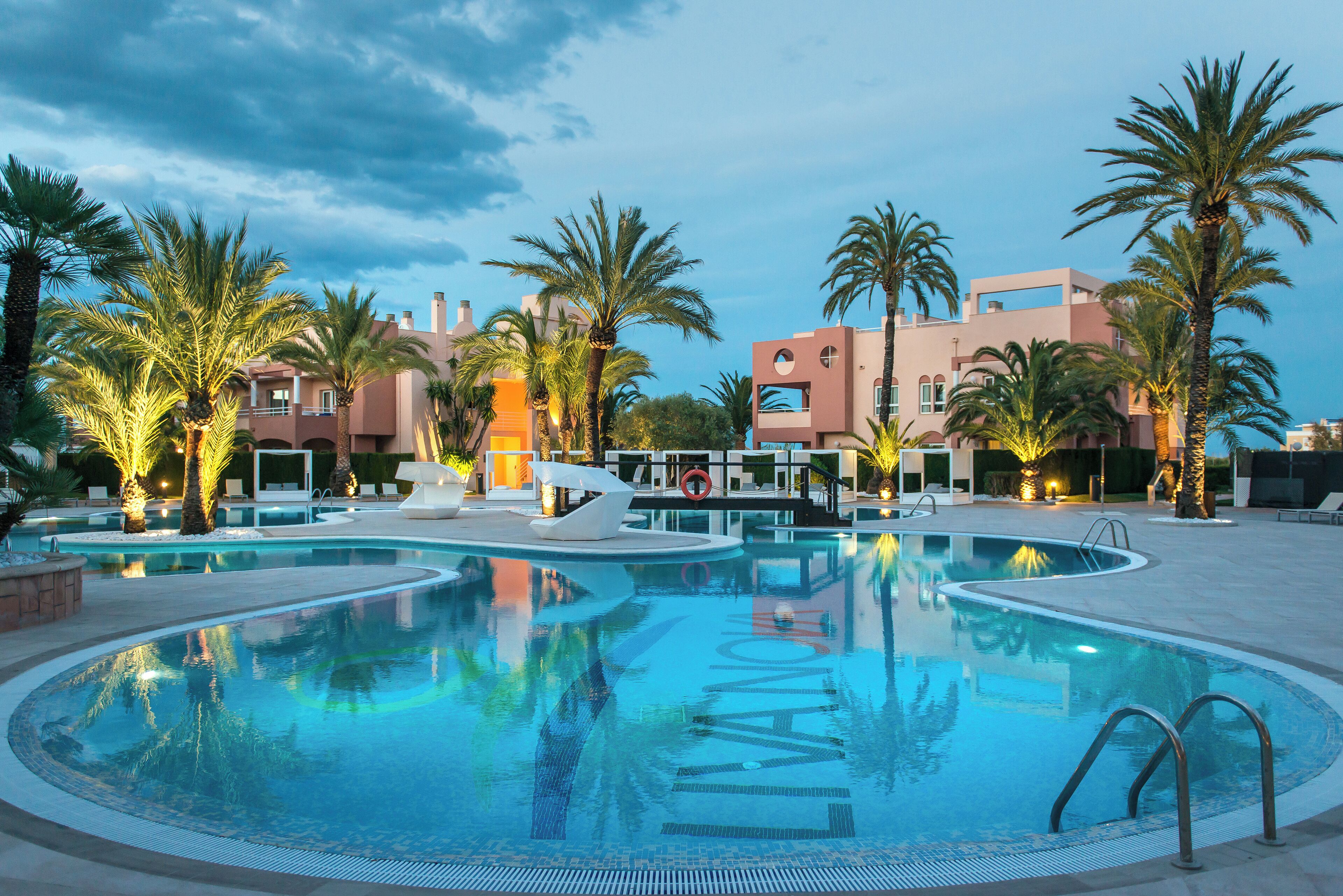 A swimming pool with a unique design, surrounded by palm trees and modern buildings.