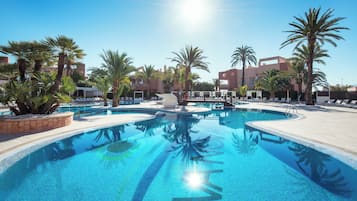 Una piscina azul cristalina rodeada de palmeras y edificios modernos.