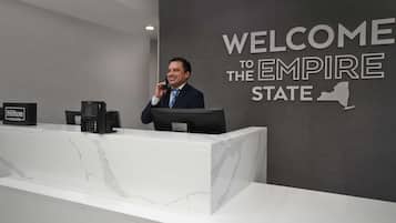 A reception desk with a "Welcome to the Empire State" sign, a phone, and a coffee machine.