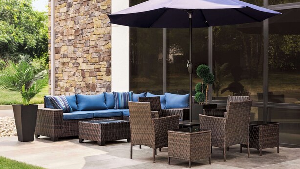 An outdoor seating area with wicker furniture, a blue sofa, and a large umbrella. - Hampton Inn Quakertown (Quakertown)