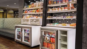 A snack bar with refrigerated display cases and shelves stocked with various snacks and beverages. - Hampton Inn Quakertown (Quakertown)