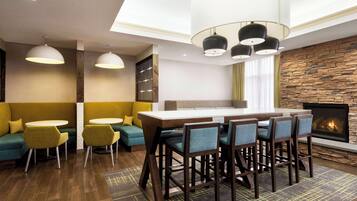 Un área de estar moderna con bar, asientos y chimenea.