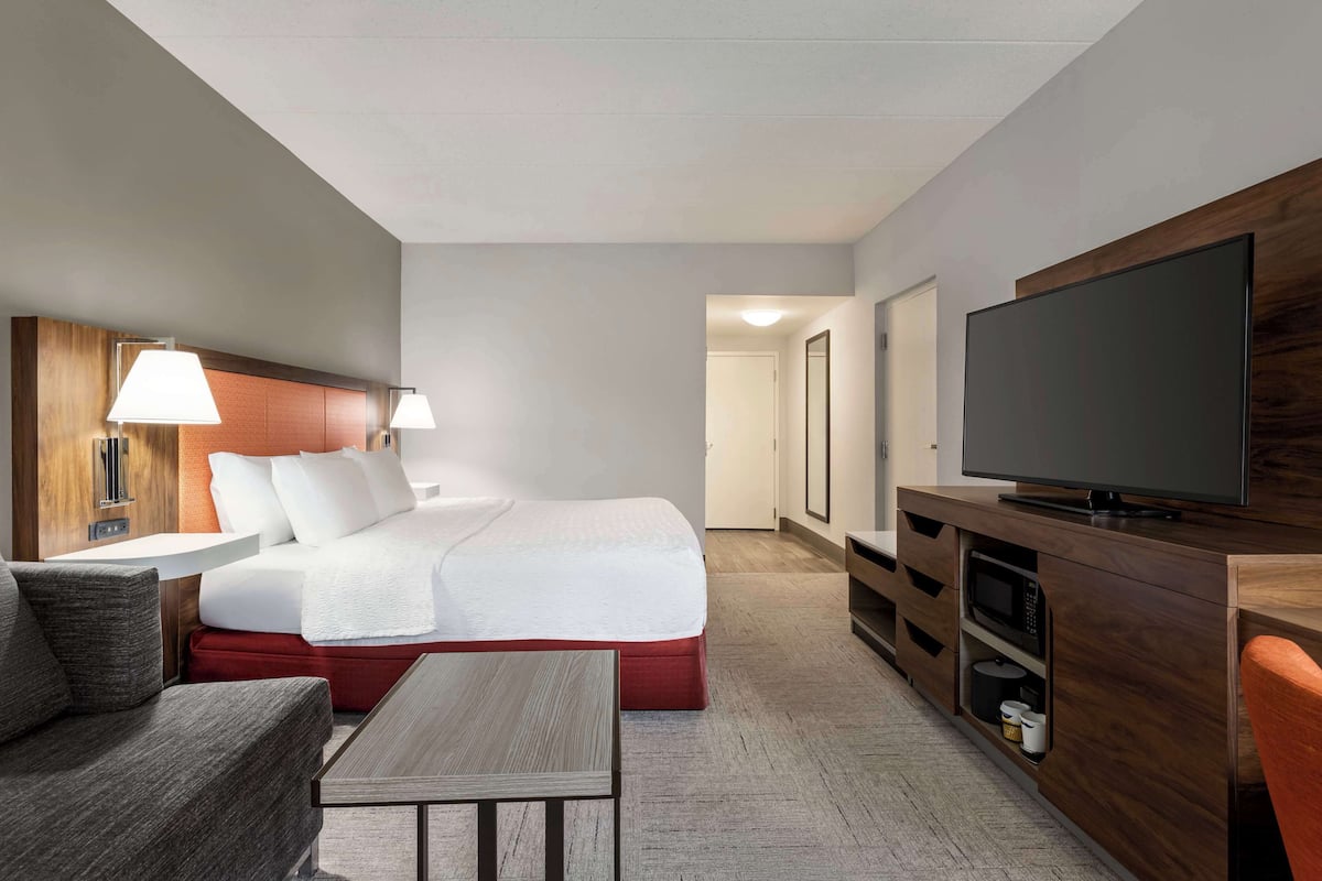 A hotel room with a bed, a TV, a desk, and a chair.