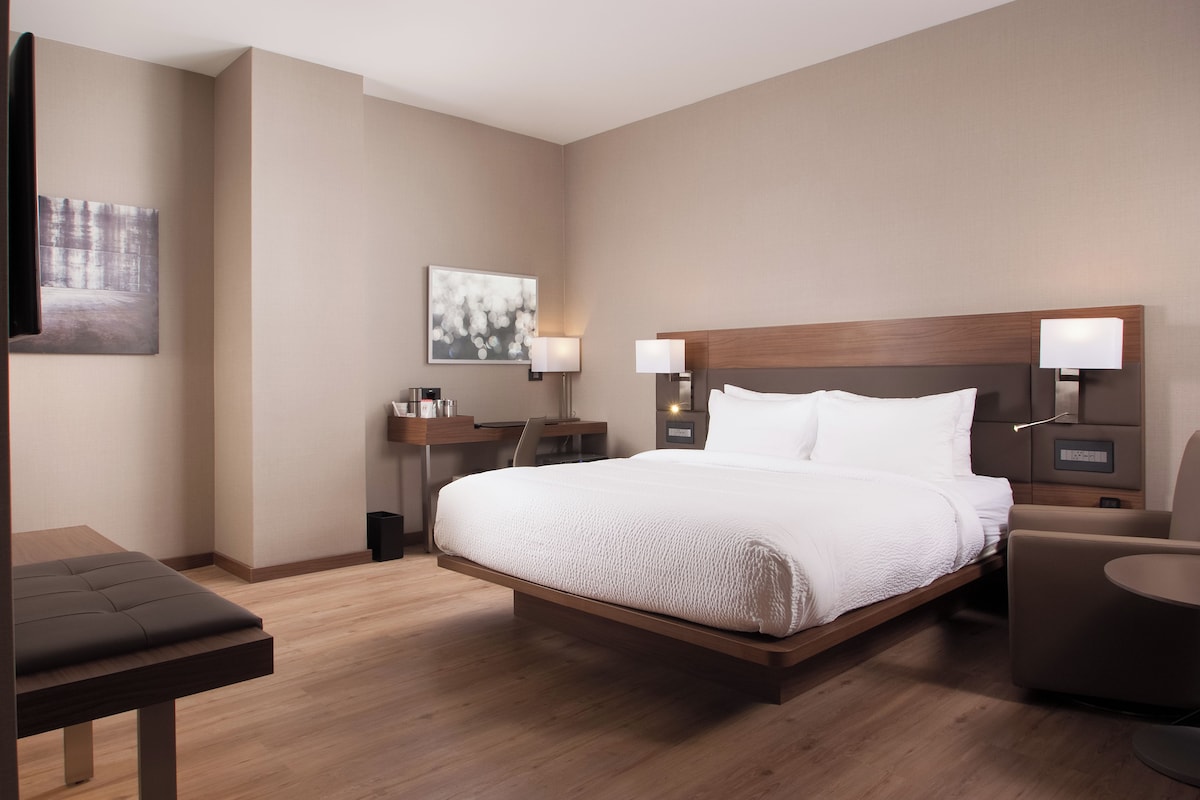 Une chambre d’hôtel avec un grand lit, des tables de chevet, un bureau et une chaise.