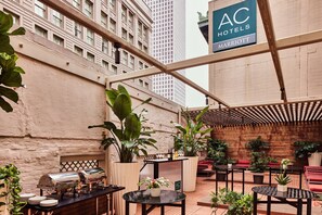 A rooftop patio with a barbecue grill, seating areas, and potted plants. - AC Hotel by Marriott New Orleans French Quarter (New Orleans)