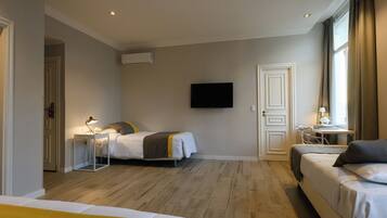 Quarto de hotel com duas camas, uma escrivaninha, uma cadeira, uma TV e uma janela.