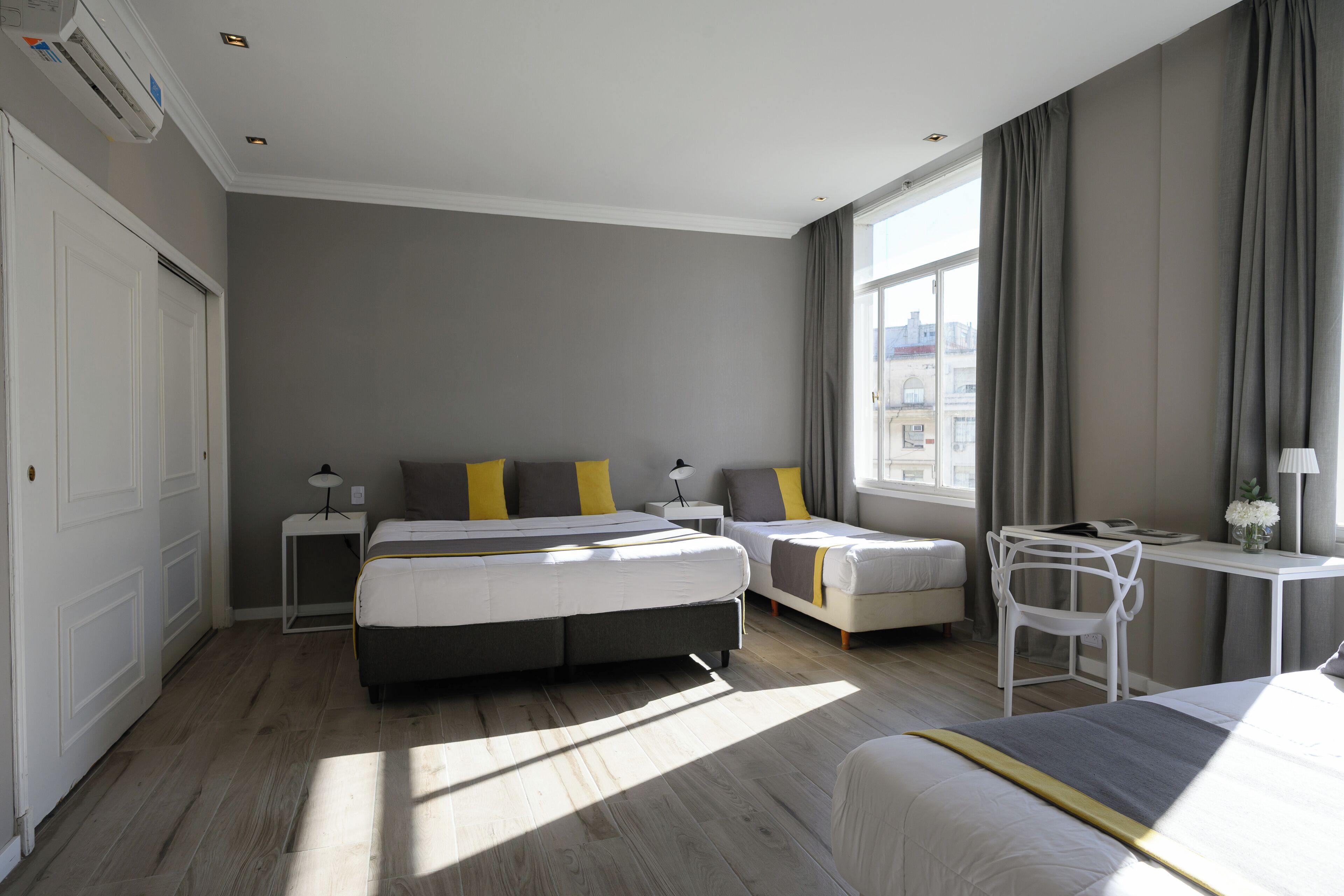 Una habitación de hotel moderna con una cama grande, otra más pequeña, un escritorio y una silla.
