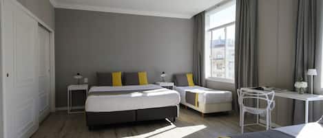 A modern hotel room with a large bed, a smaller bed, a desk, and a chair.