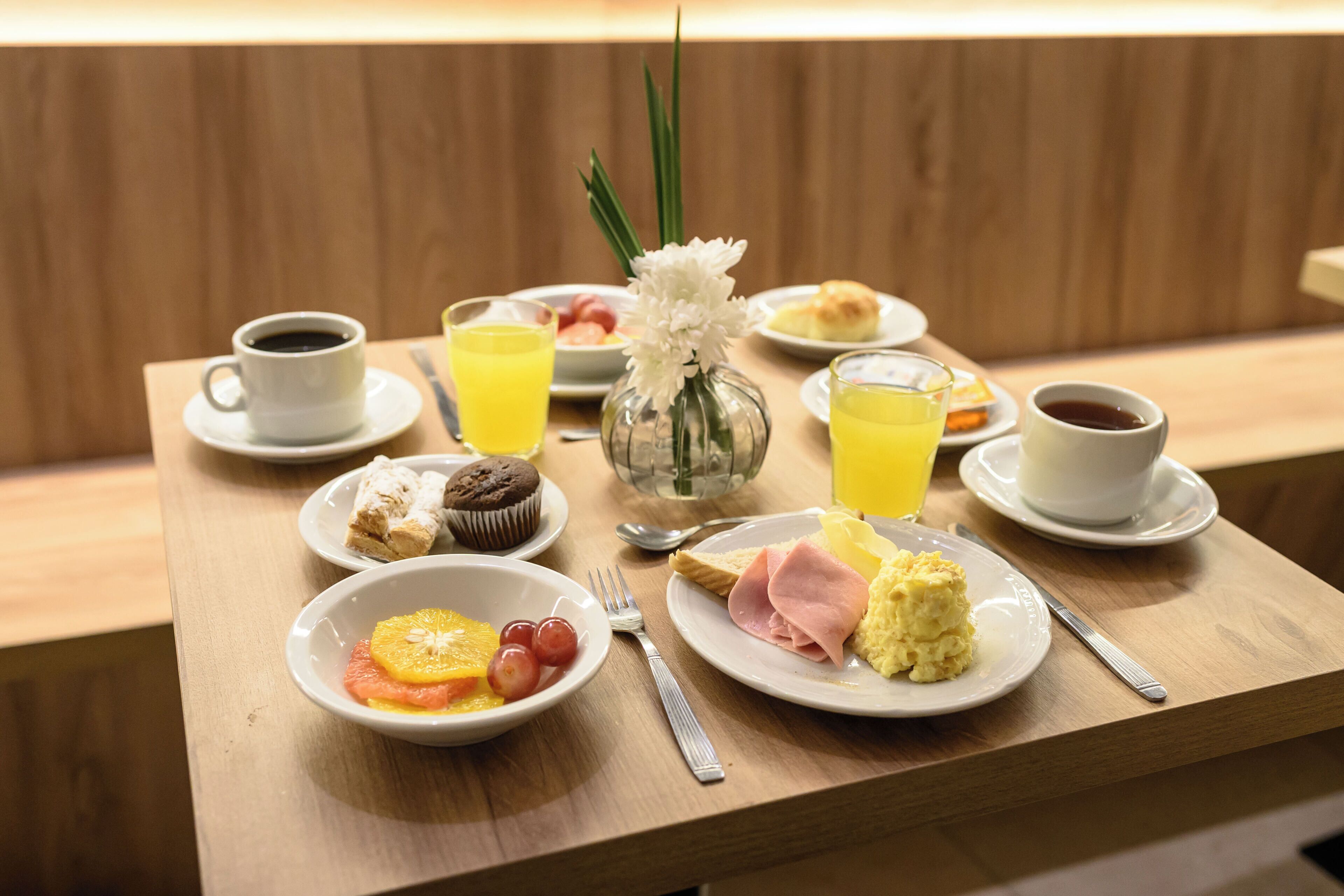 A breakfast table with plates of food, a coffee cup, and a glass of orange juice.