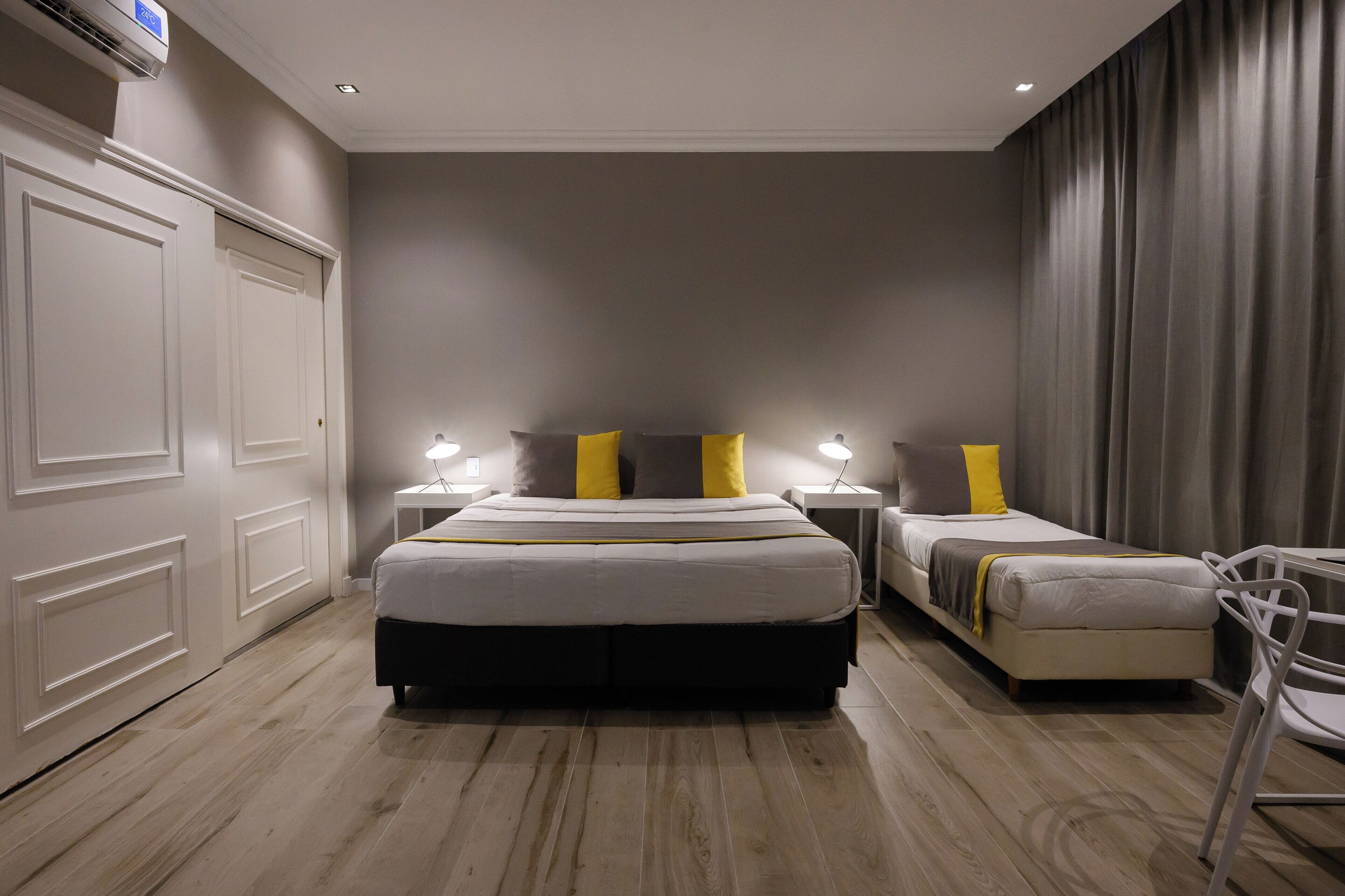 Un dormitorio con una cama grande, dos mesitas de noche, una silla y un armario.