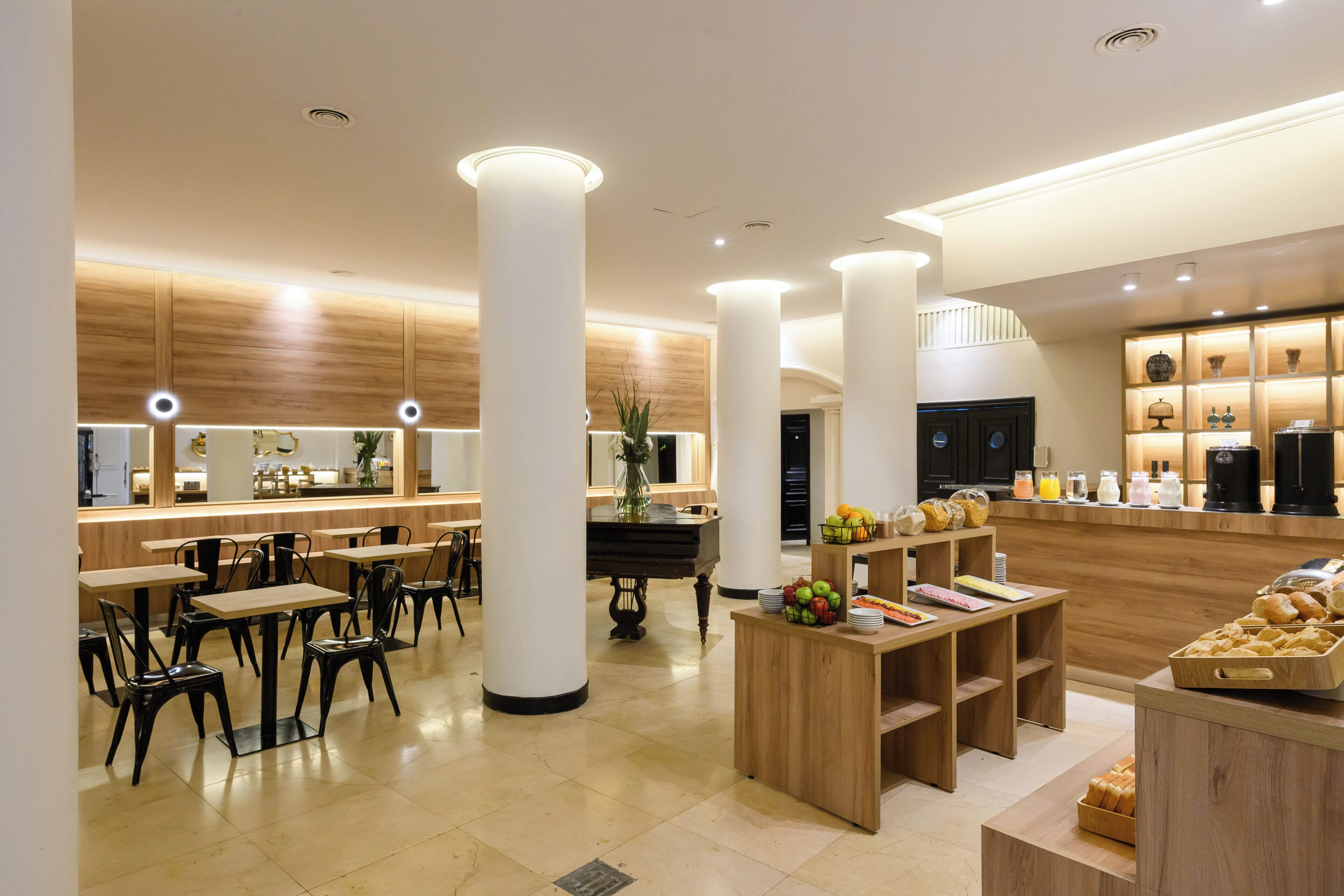 A modern hotel lobby with a reception desk, seating area, and a coffee station.