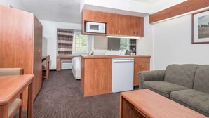 A compact room with a kitchenette, a sofa, a dining table, and a small window. - Microtel Inn & Suites by Wyndham Rice Lake (Rice Lake)