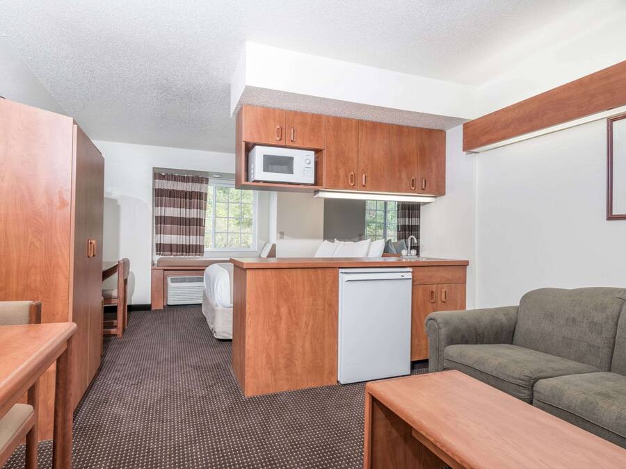 A compact room with a kitchenette, a sofa, a dining table, and a small window.