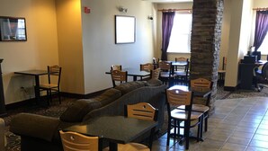 A hotel lobby with a seating area featuring a sofa, chairs, and a dining table. - Microtel Inn & Suites by Wyndham Rice Lake (Rice Lake)