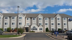 A multi-story hotel with a symmetrical facade, a central entrance, and a parking lot with several cars. - Microtel Inn & Suites by Wyndham Rice Lake (Rice Lake)