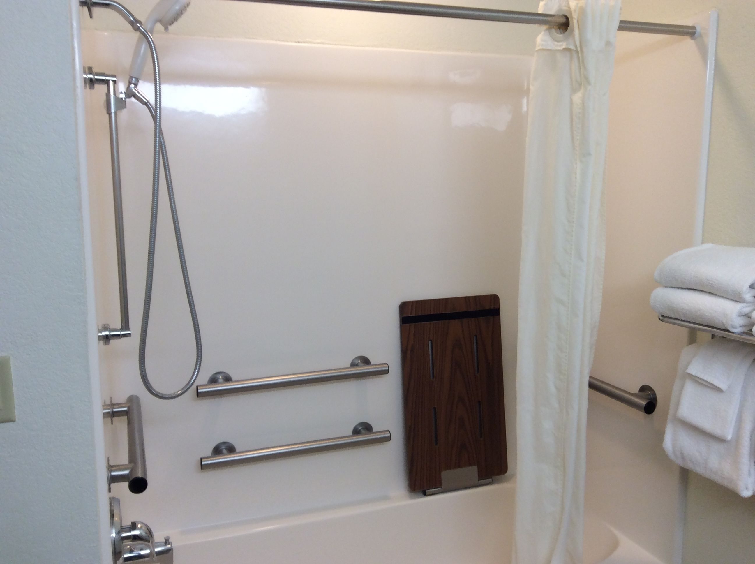 A bathroom with a shower, a towel rack, and a wooden cabinet.