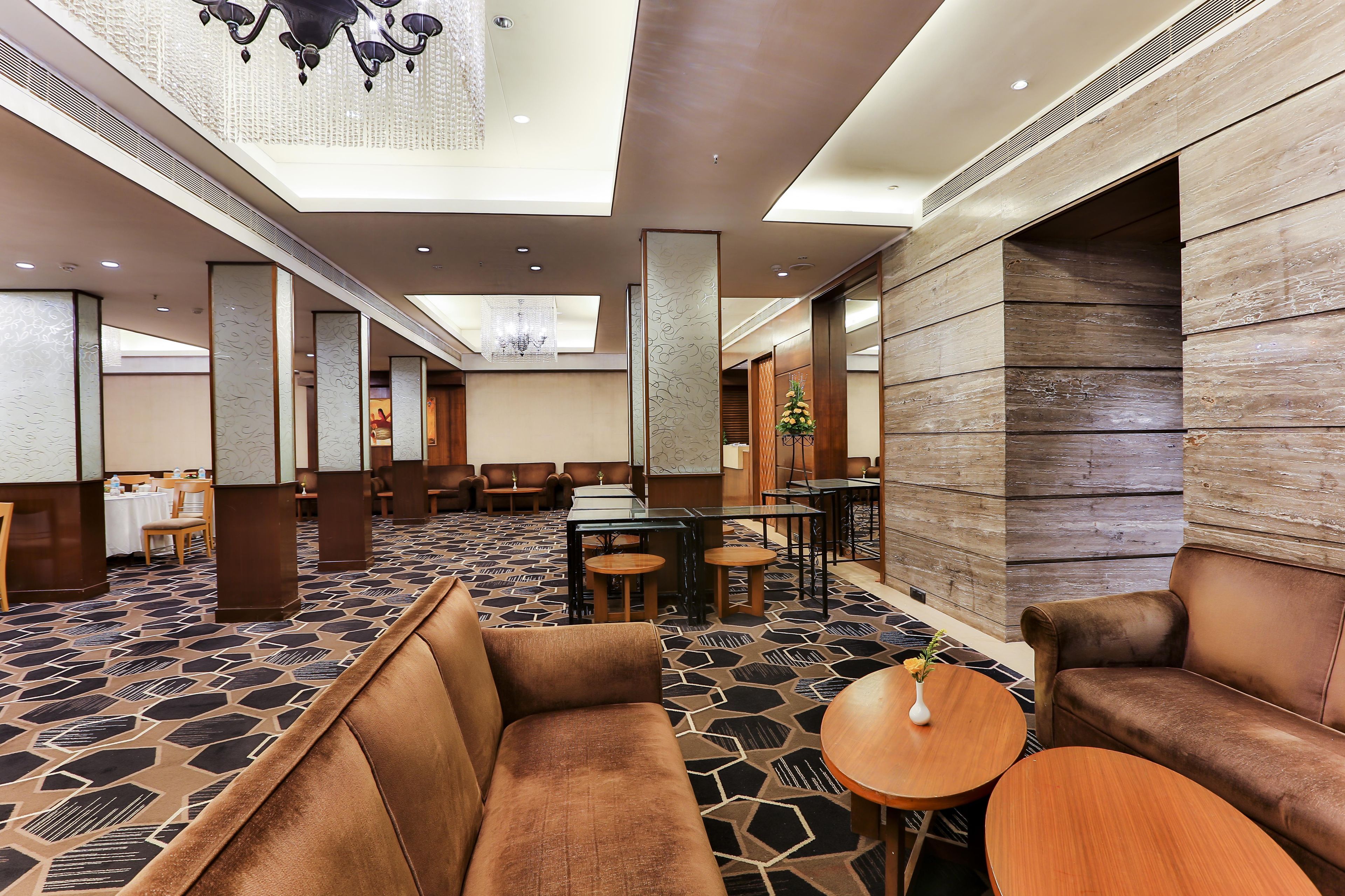 Un hall d’hôtel avec un sol à motifs, des fauteuils en cuir et un lustre.