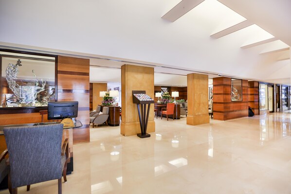 A spacious lobby with a reception desk, seating area, and a modern design with wooden accents and a polished floor. - Sun N Sand Hotel Mumbai (Mumbai)