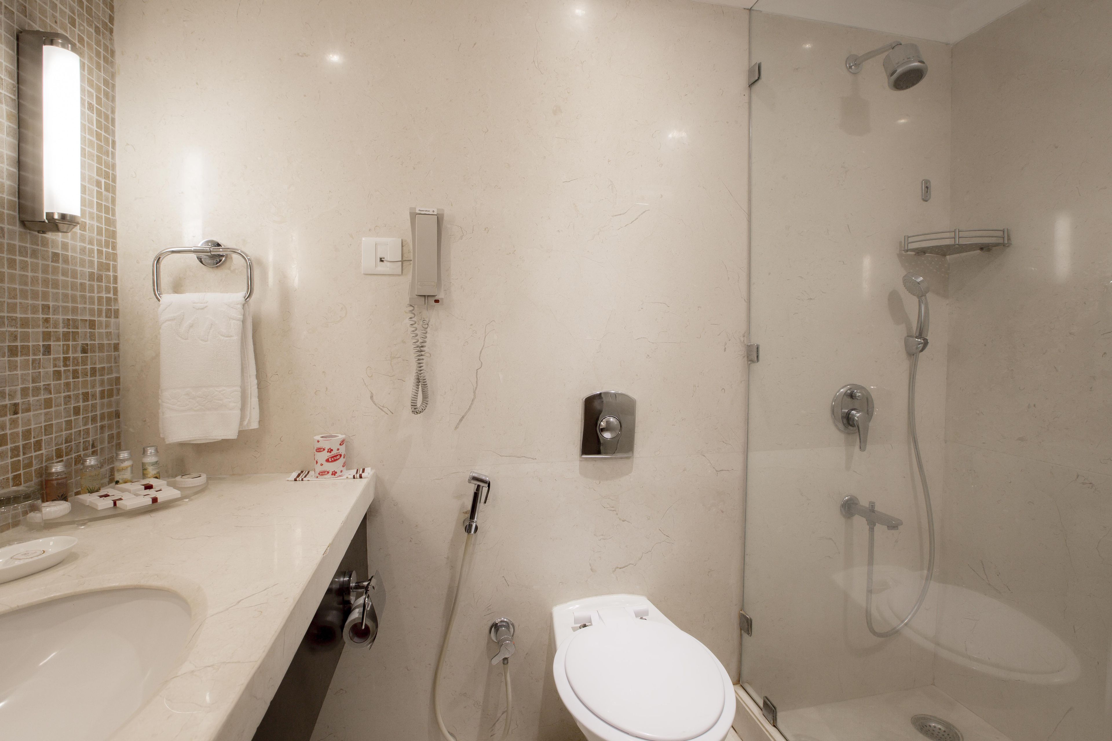 Une salle de bain moderne avec un lavabo en marbre, des toilettes et une douche séparée par une paroi de verre.