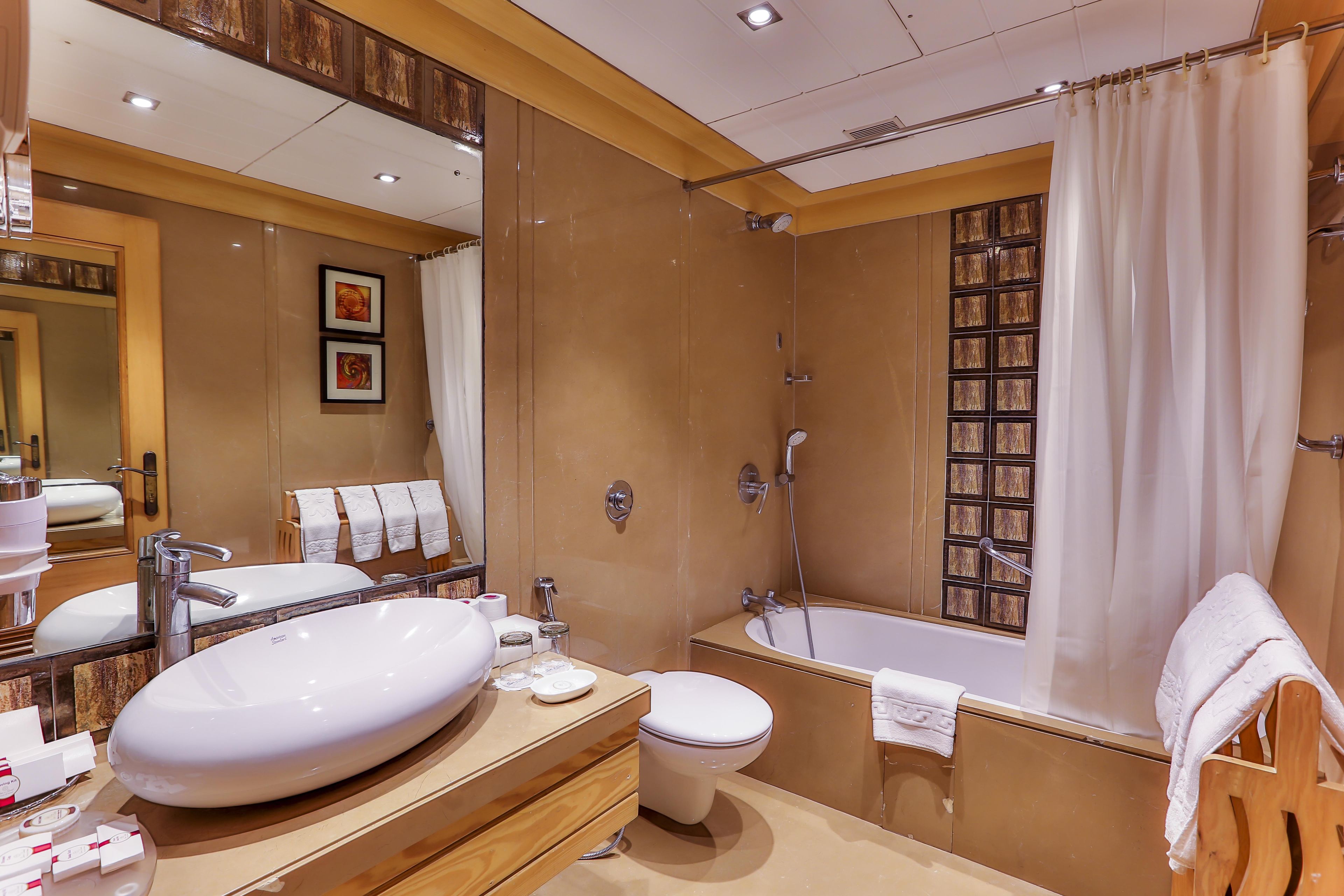 Un baño moderno con un lavamanos ovalado grande, un inodoro separado y una bañera independiente.
