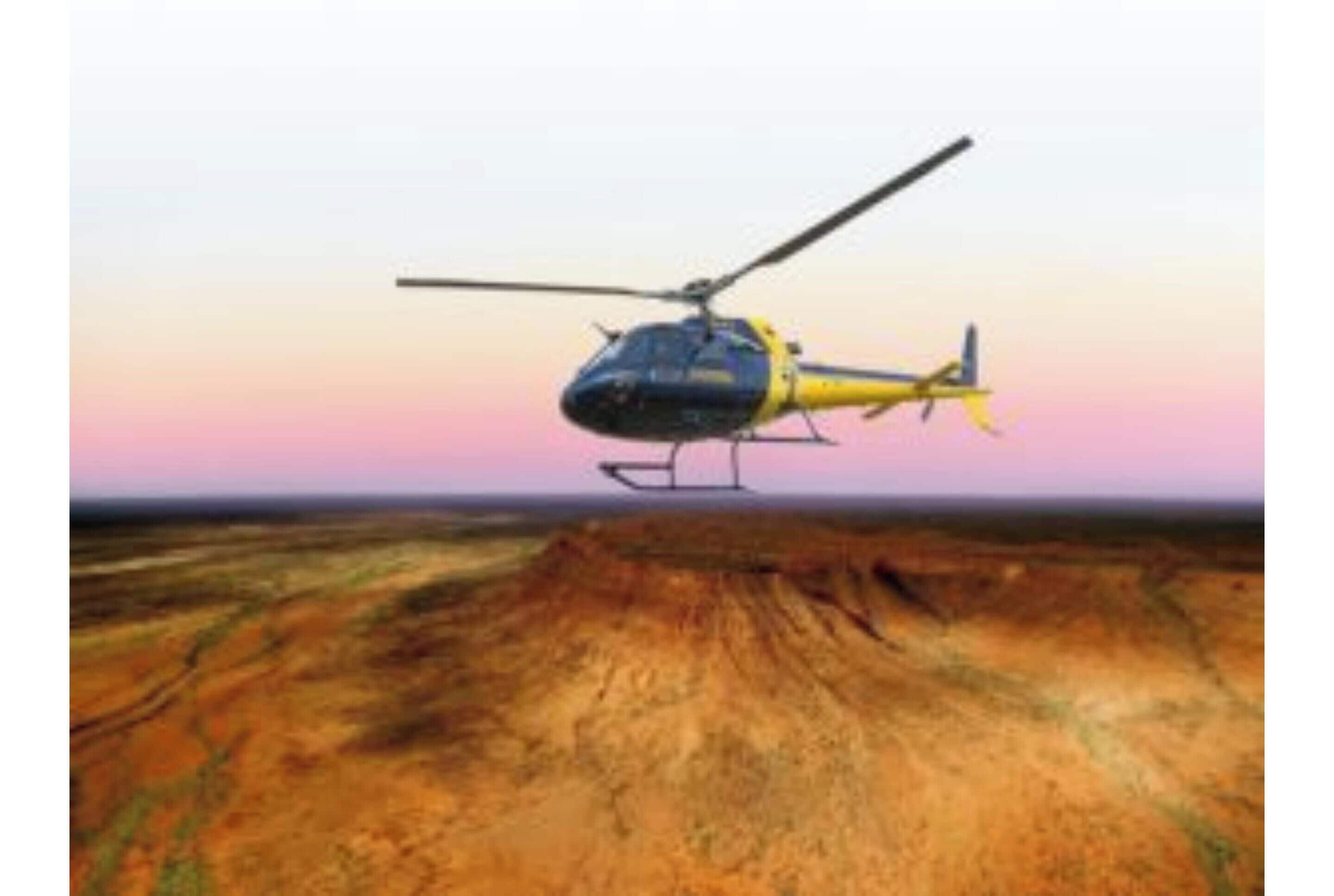 A helicopter in flight over a barren landscape.