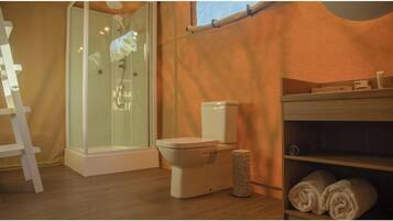A bathroom with a shower, toilet, and shelves with towels.
