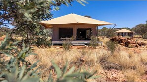 A desert-style tent with a flat roof, surrounded by dry grass and sparse vegetation. - Discovery Resorts - Kings Canyon (Petermann)