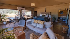 A spacious room with a large bed, a sofa, a dining area, and a view of the outdoors. - Discovery Resorts - Kings Canyon (Petermann)