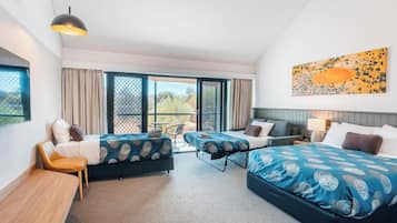 Quarto de hotel com duas camas, uma mesa, uma cadeira e varanda com vista.