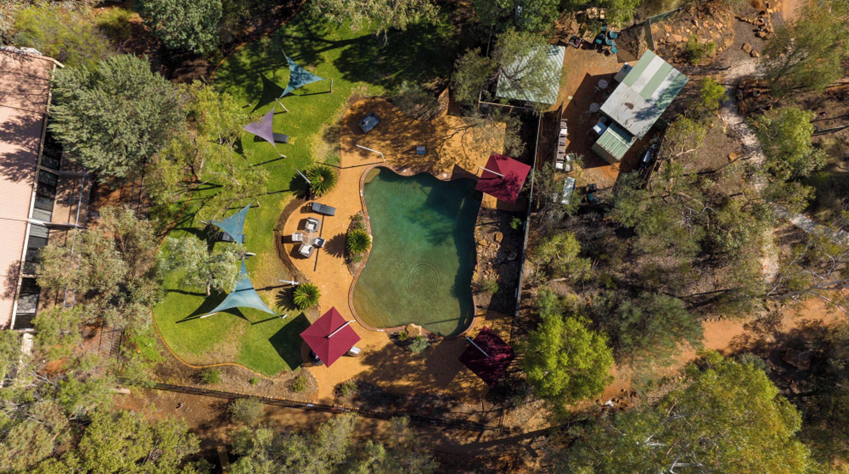 An aerial view of a campsite with a swimming pool, picnic tables, and tents.
