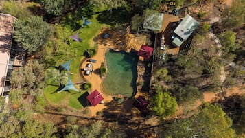 An aerial view of a campsite with a swimming pool, picnic tables, and tents.