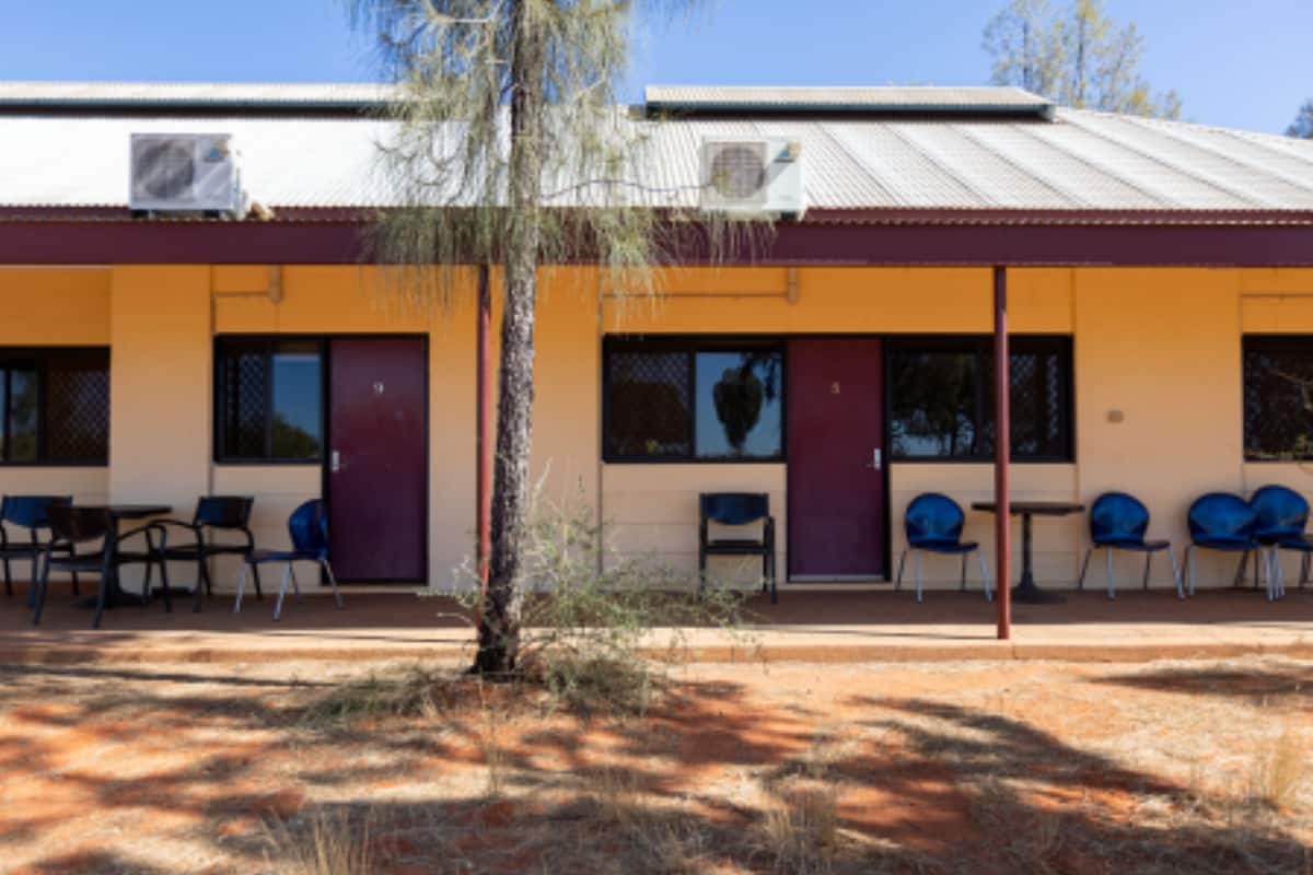 A building with a yellow exterior, multiple windows, and a tree in front.