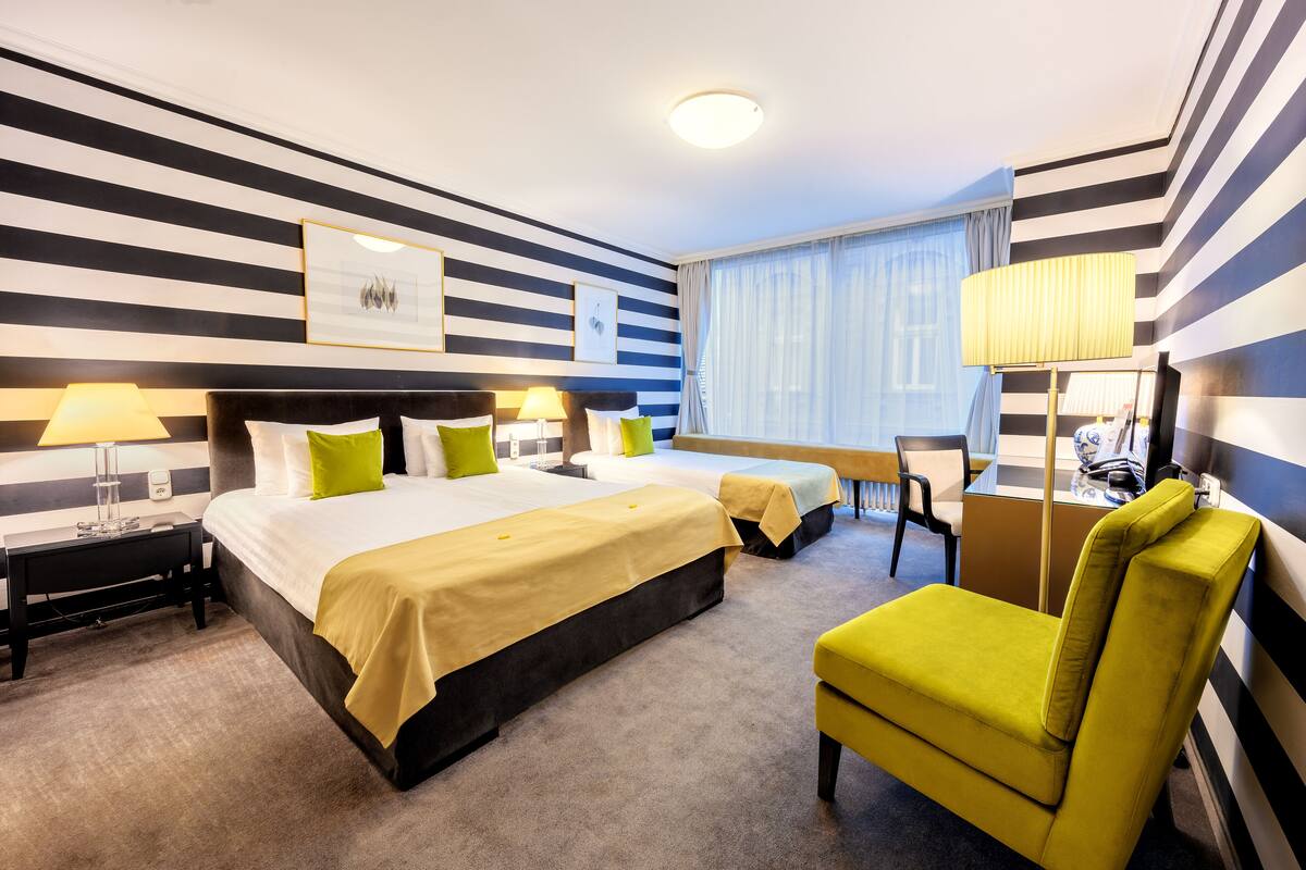 A hotel room with a large bed, two bedside tables, a chair, and a desk.