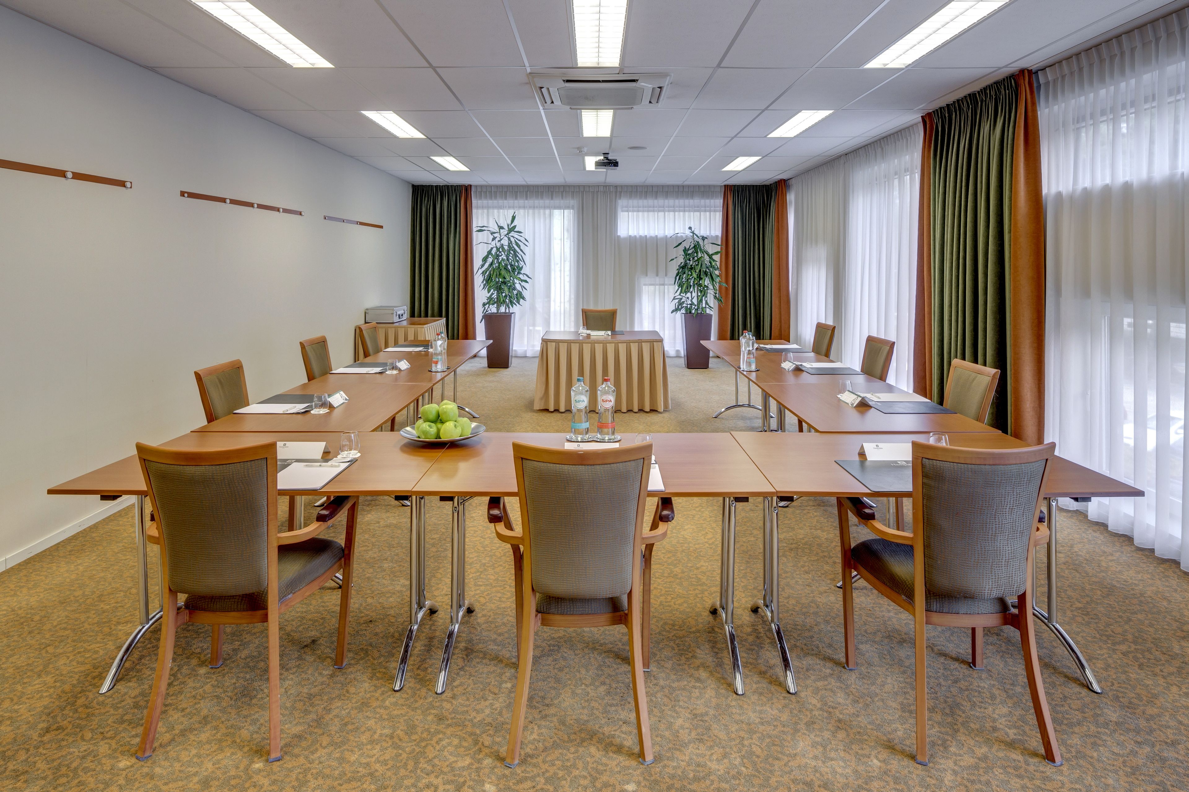 A conference room with a long table, chairs, and a projector screen.