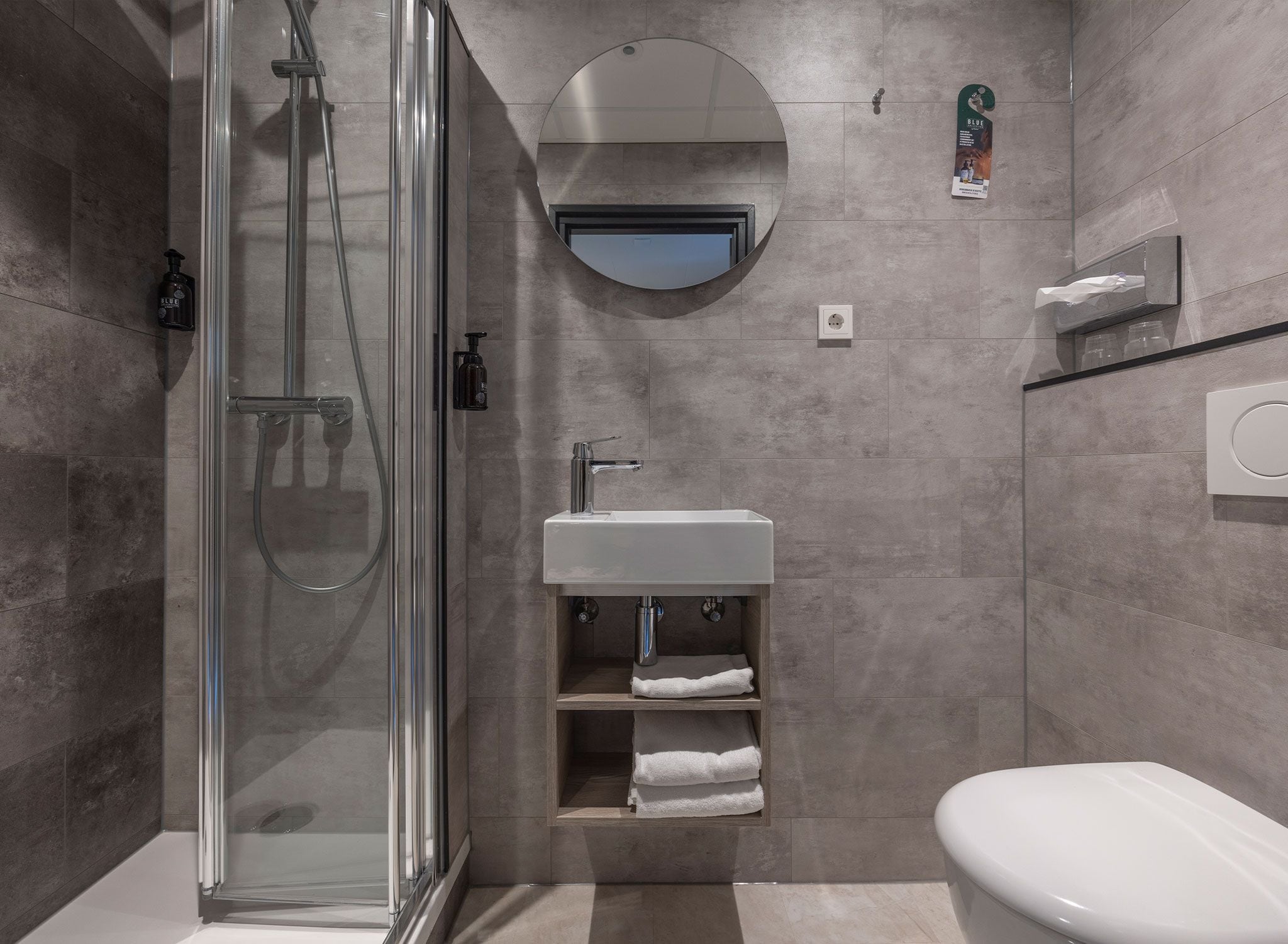Ein modernes Badezimmer mit einer gläsernen Duschkabine, einem Waschbecken mit Spiegel darüber und einer Toilette.