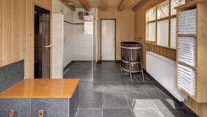 A wooden interior with a tiled floor, a wooden table, and a radiator. - Fletcher Hotel-Restaurant Mooi Veluwe (Putten)