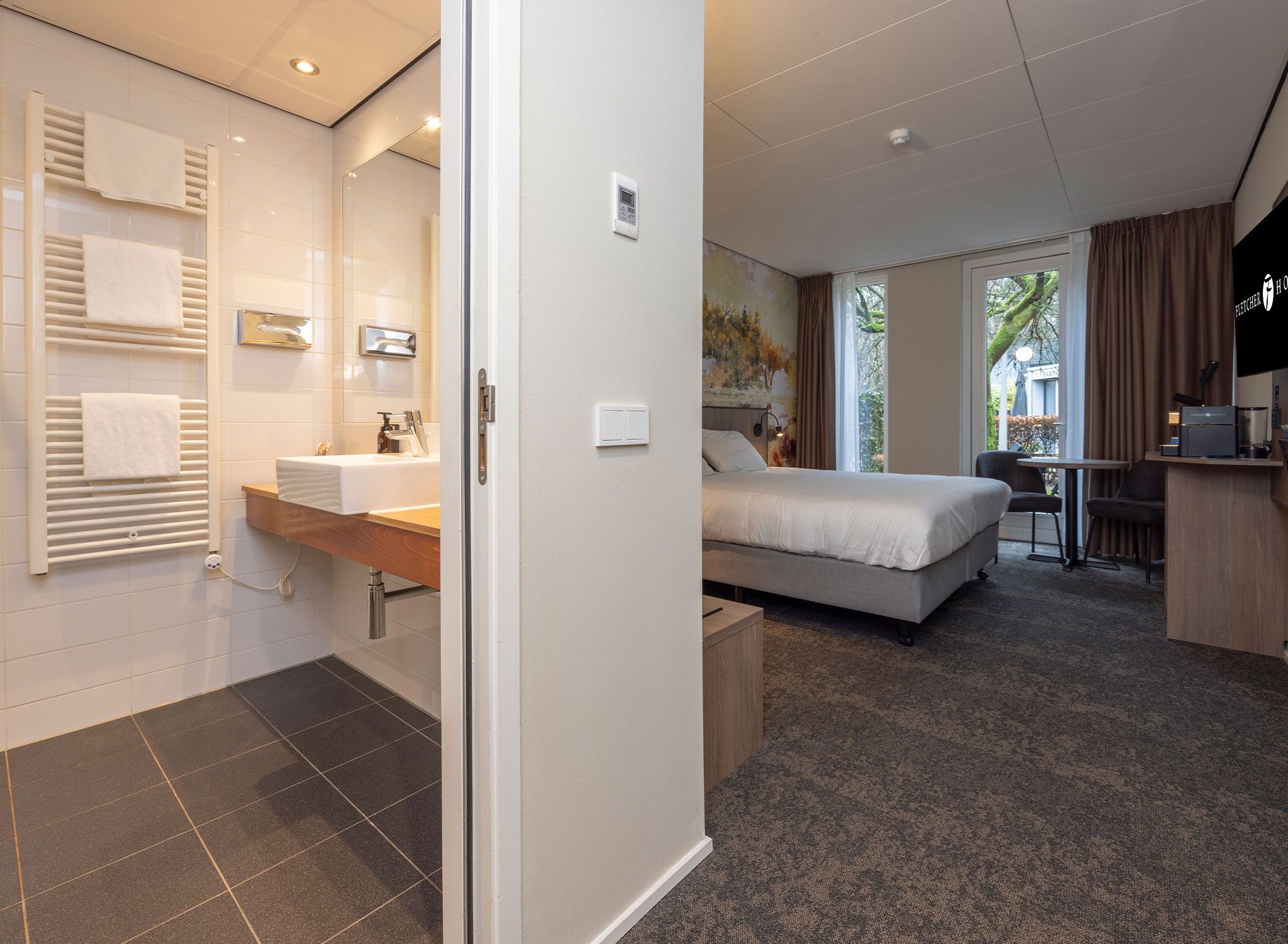 Une chambre d’hôtel comprenant un lit, un bureau, une salle de bain avec douche et une vue sur l’extérieur.