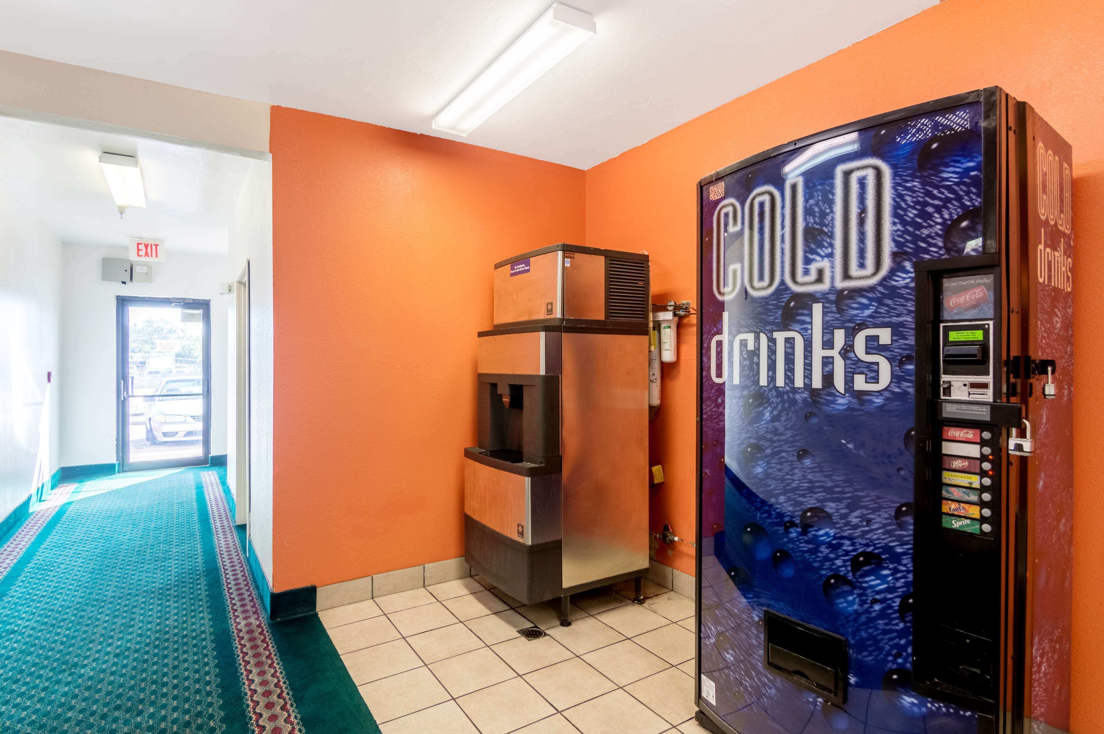 Ein Flur mit einer orangefarbenen Wand, einem Automaten mit der Aufschrift 'COLD drinks' und einem Wassenspender.