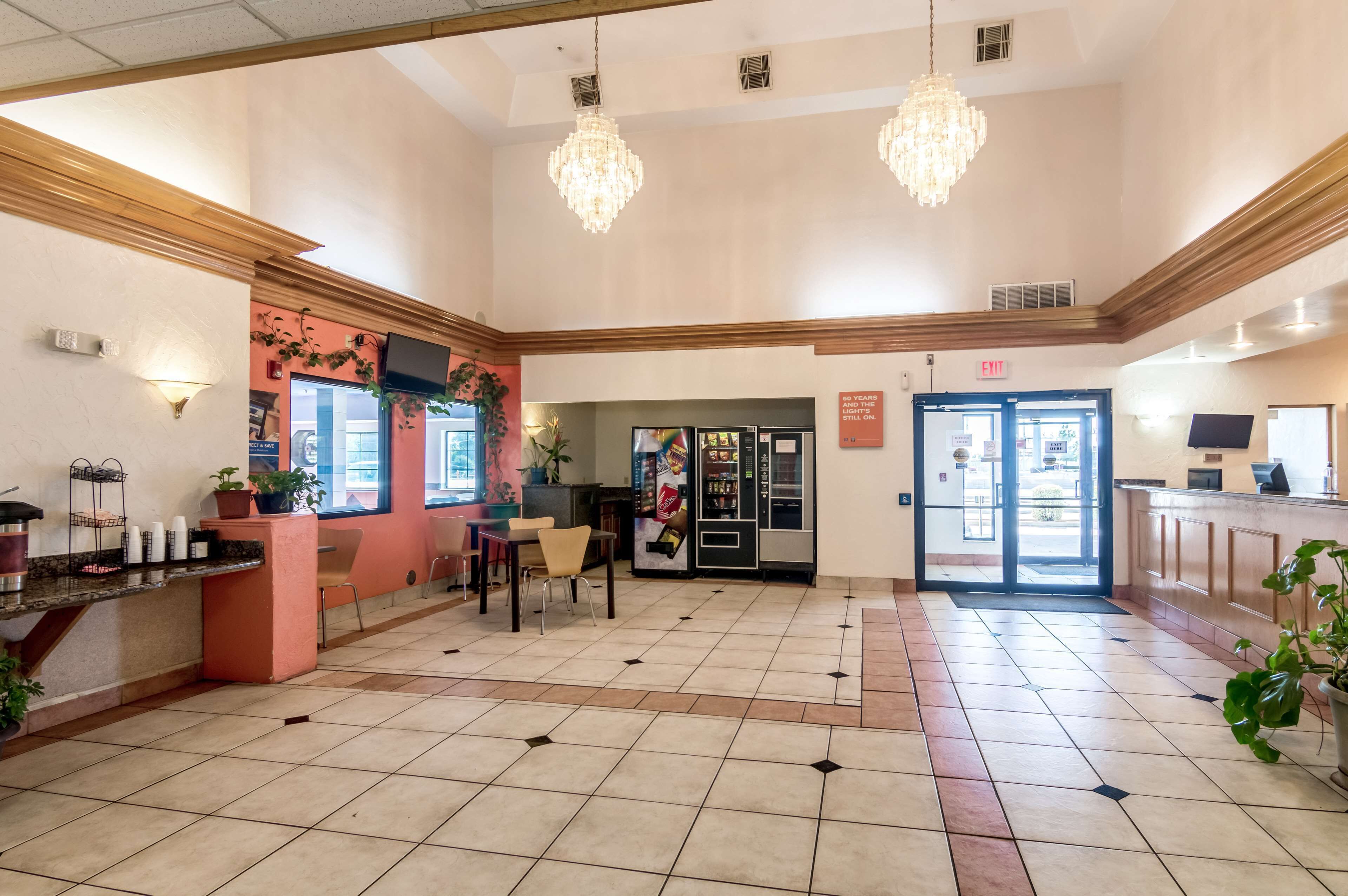 A spacious lobby with a reception desk, seating area, and a glass door entrance.