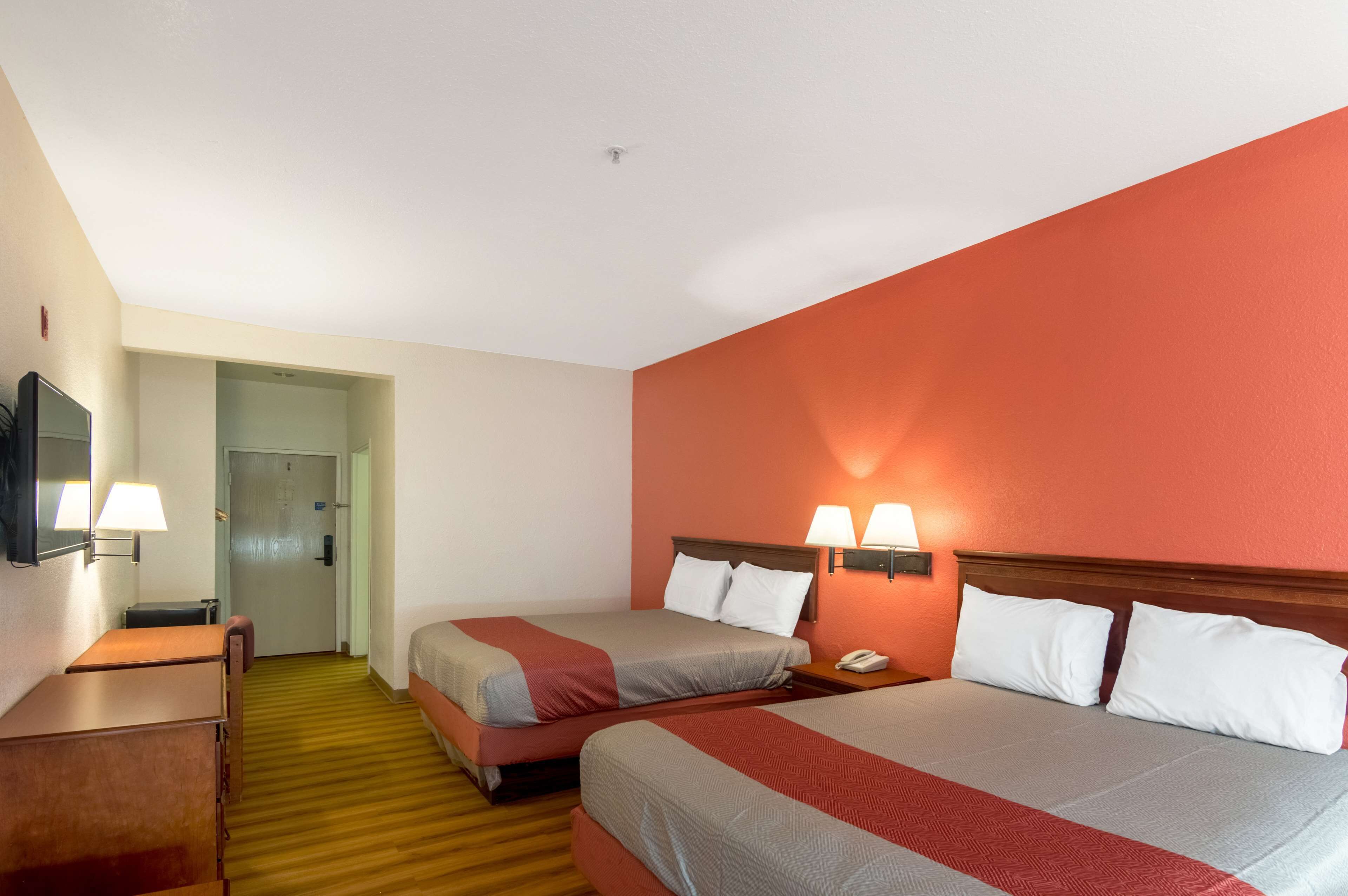 A hotel room with two beds, a desk, a chair, and a television.