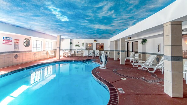 Una piscina interior con techo que simula un cielo azul. Hay sillas de descanso y una estación de socorristas.