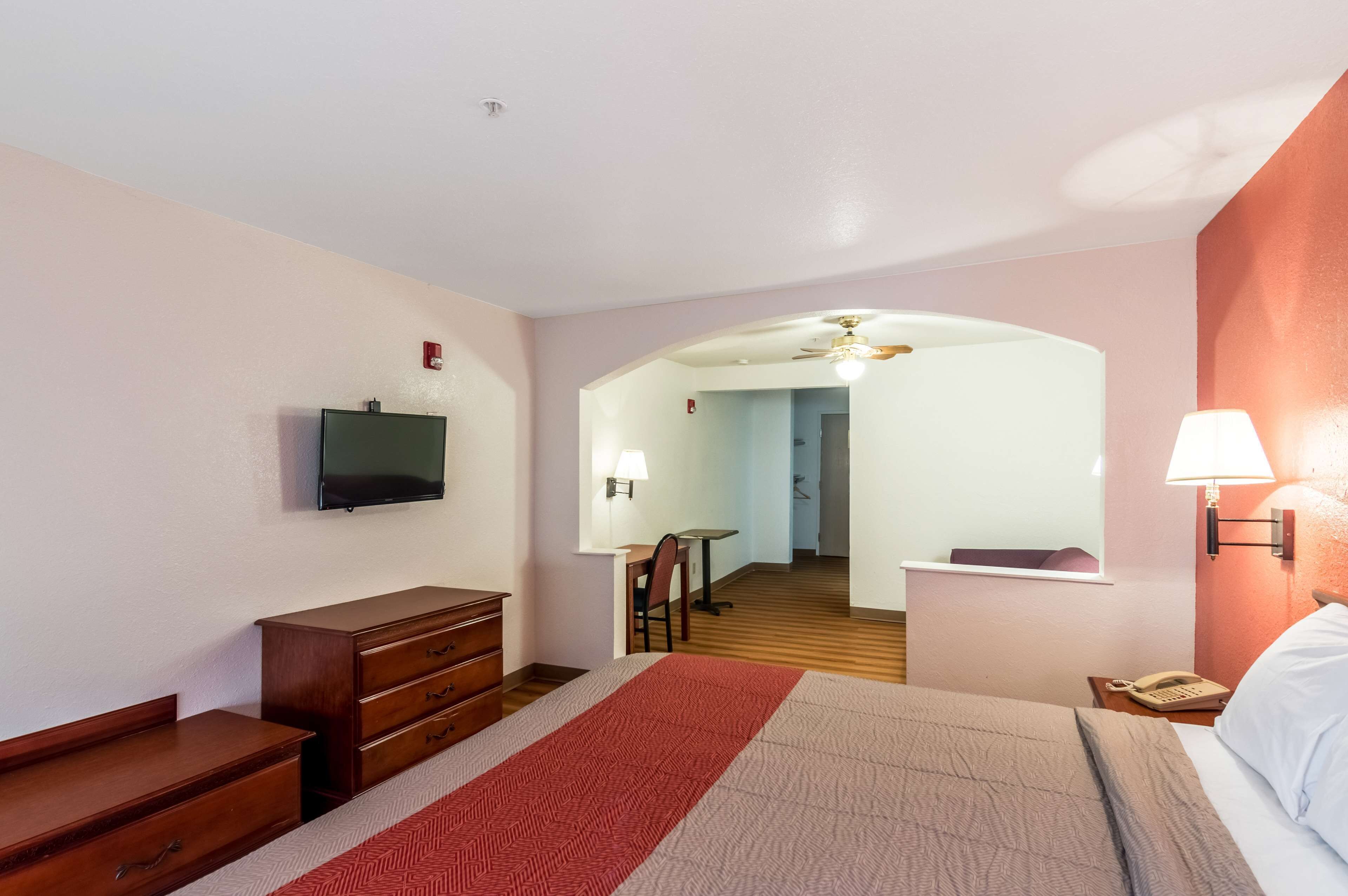 A hotel room with a bed, a TV, a desk, and a chair.