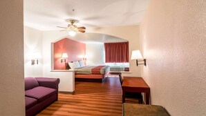 Habitación de hotel con cama, escritorio, silla, sofá y ventilador de techo.