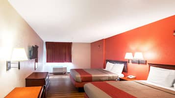 Une chambre d’hôtel avec deux lits, un bureau, une chaise, une lampe, une télévision et une fenêtre avec des rideaux.