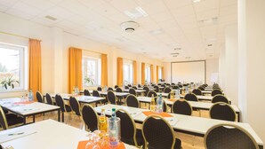 A conference room with multiple tables and chairs, equipped with water bottles and documents. - Trip Inn Hotel Astoria Göttingen (Goettingen)