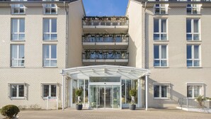 A multi-story hotel with a glass entrance, potted plants, and a sign indicating a parking area. - Trip Inn Hotel Astoria Göttingen (Goettingen)